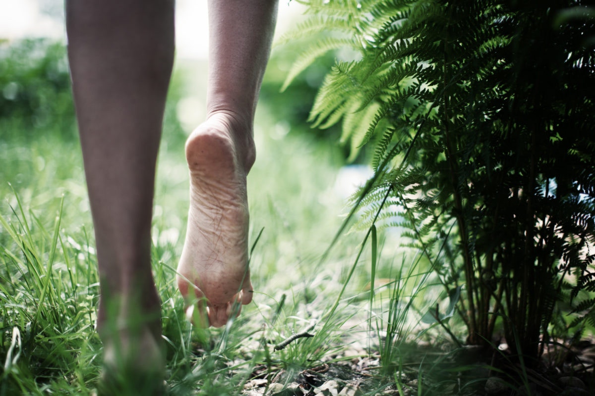 Young man walking barefoot across a grassy field