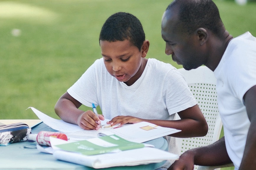 Young boy doing his school homework with his father.