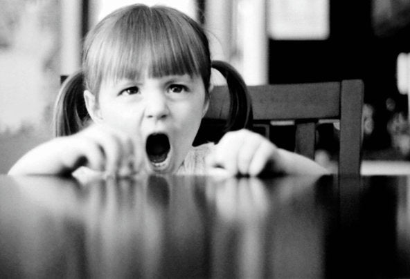 little baby girl sitting at table and screaming