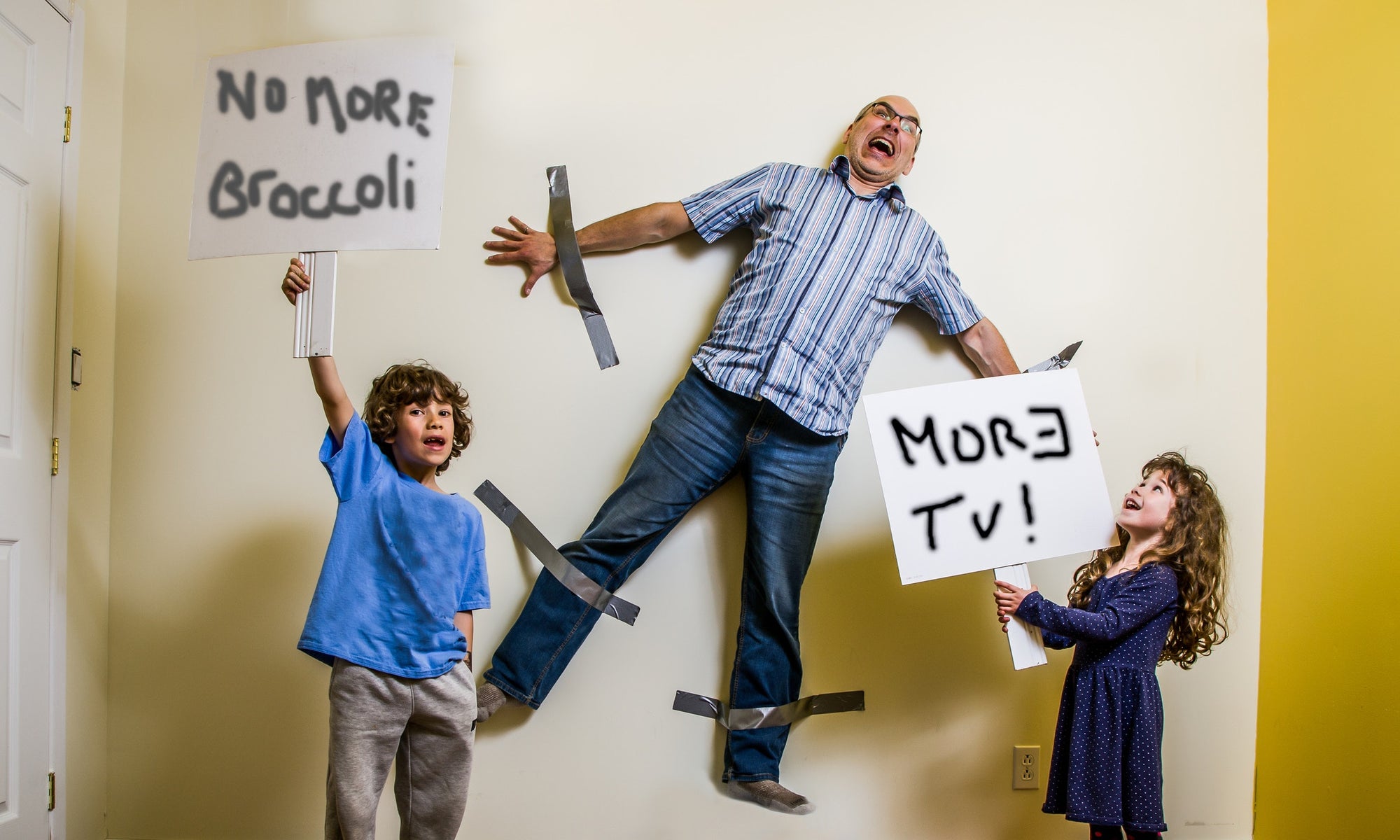 children standing  with boards father sticked on the wall behind them