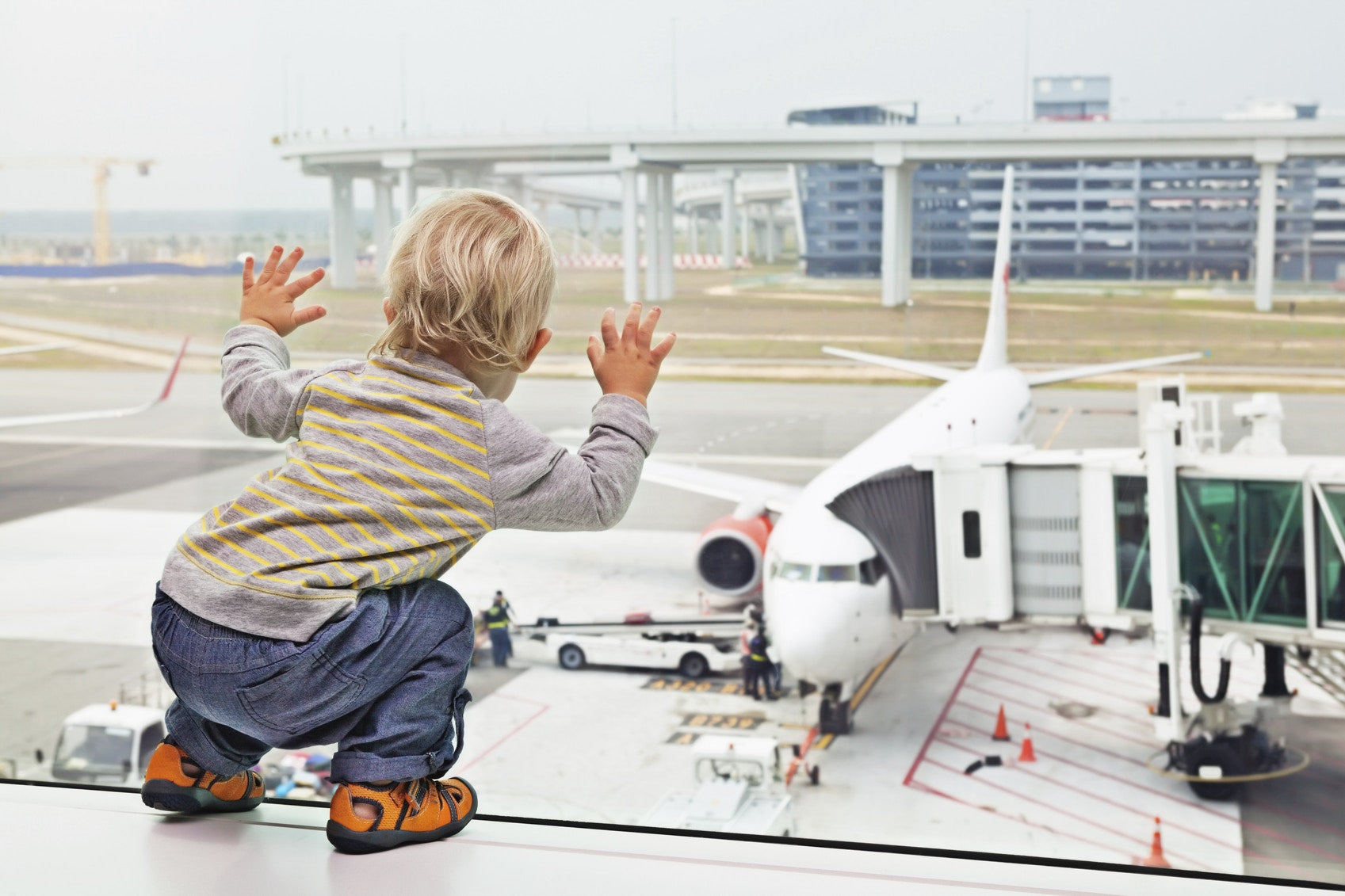 Toddler watching an airplane from lounge