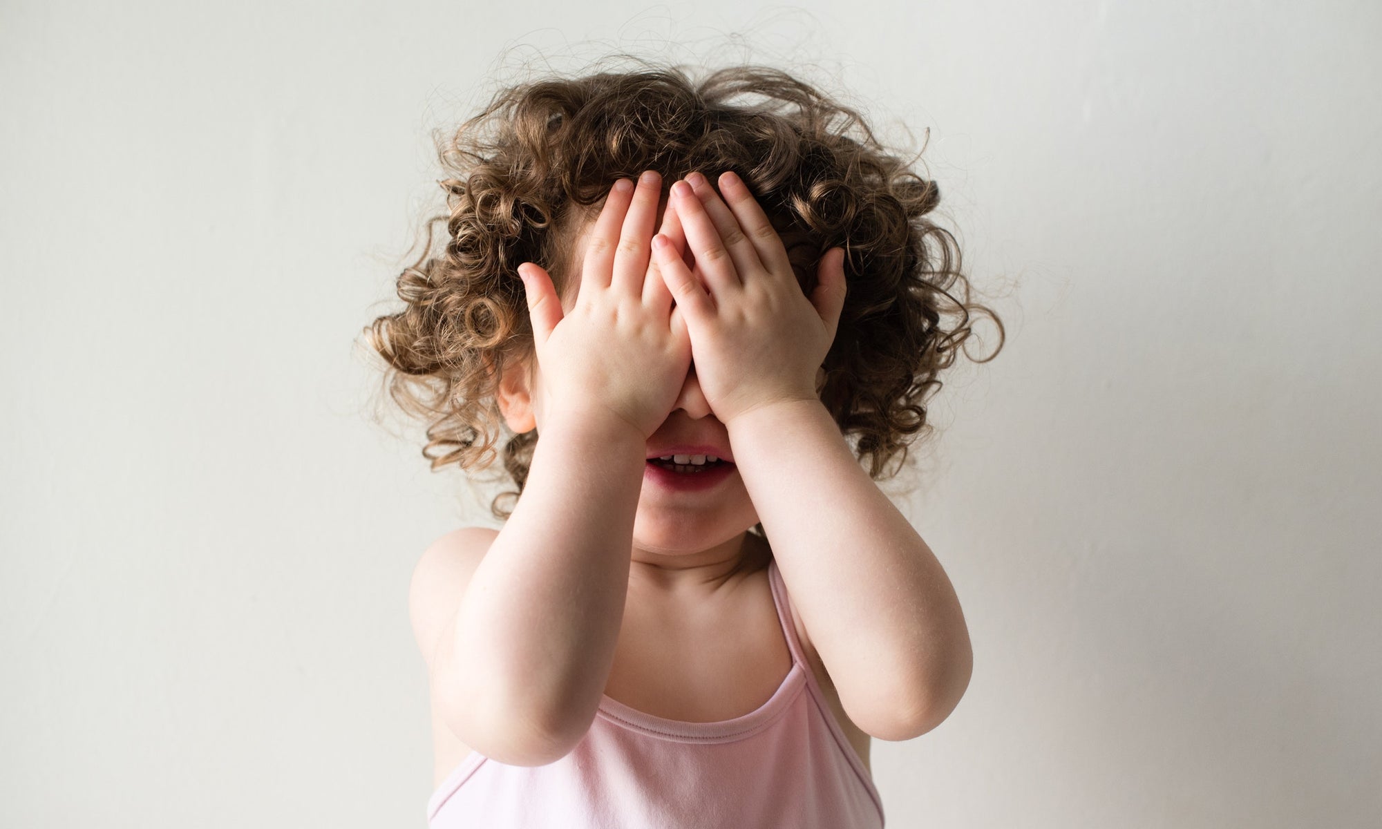 A baby girl closing eyes using hand