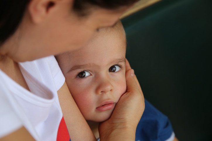 A baby watching its mother from the arms