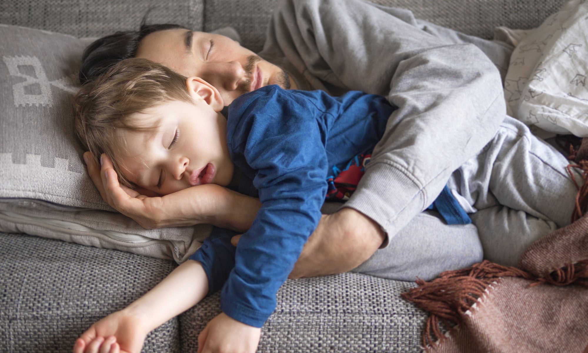 Father and baby boy sleeping on bed 