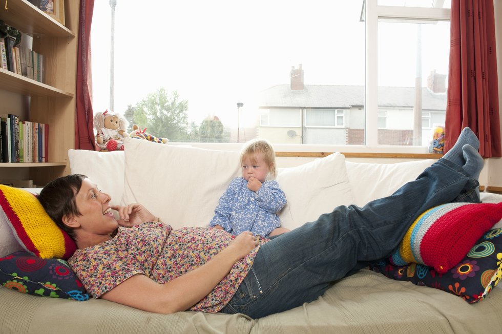 happy mother lying on couch with her baby