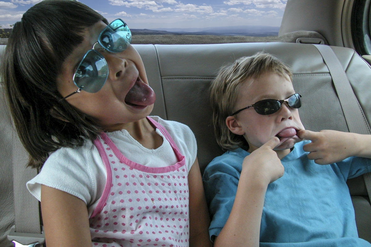 children making funny faces sitting at the car