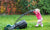 Cute curly baby girl  with big green lawn mower