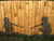 Shadow of two kids holding out their hands to hold each other on a wooden wall