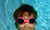 young boy wearing swimming googles and holding his breath underwater in apool