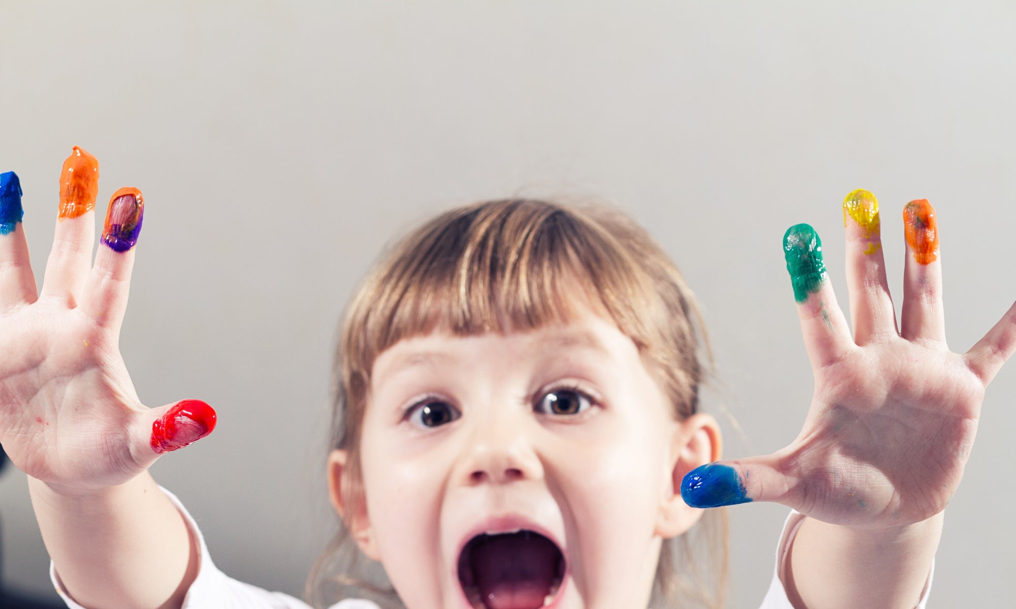 Little girl showing her hands, covered in finger paint after painting a picture