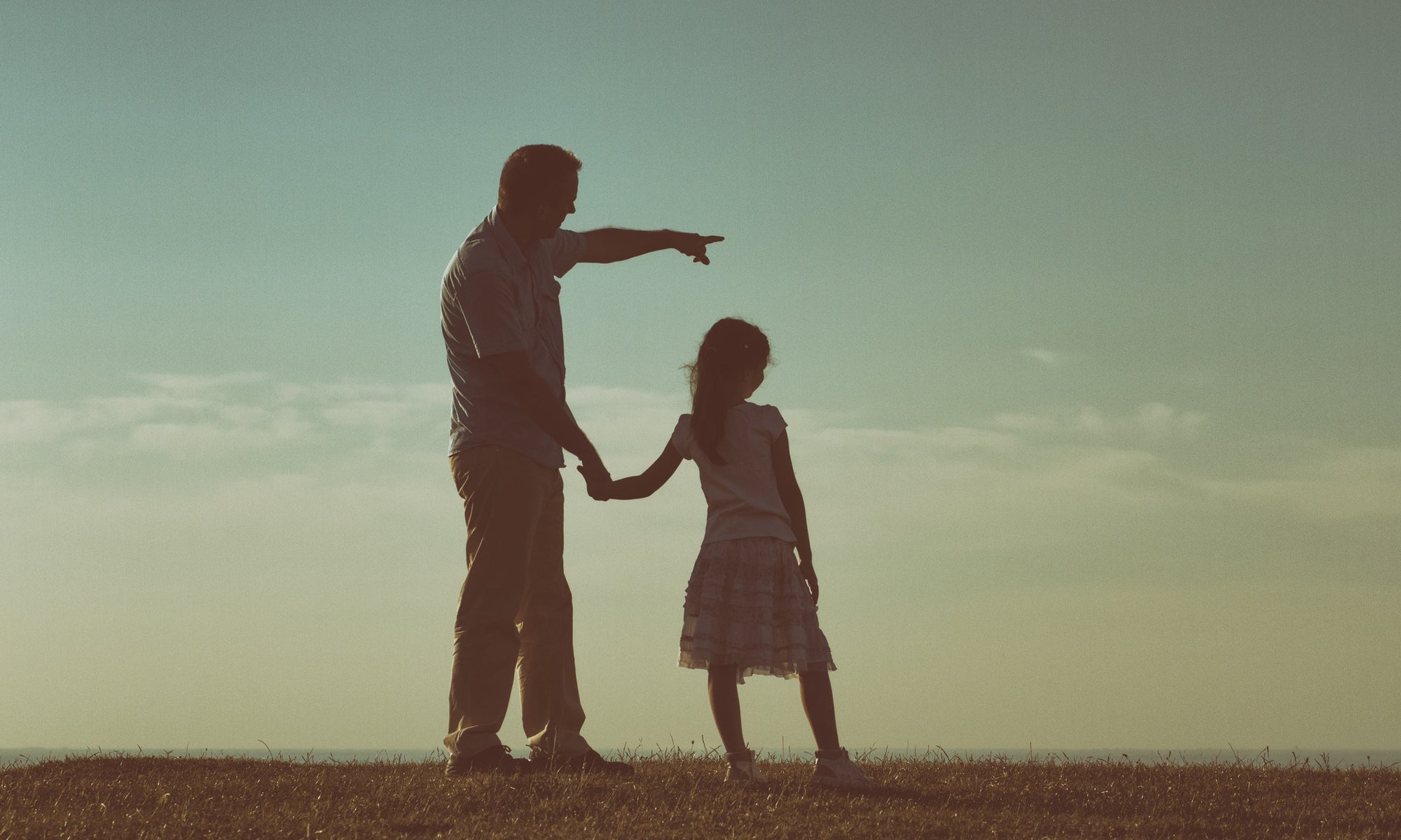 Father and daughter holding hands standing on a hill with nature lanscape back view.