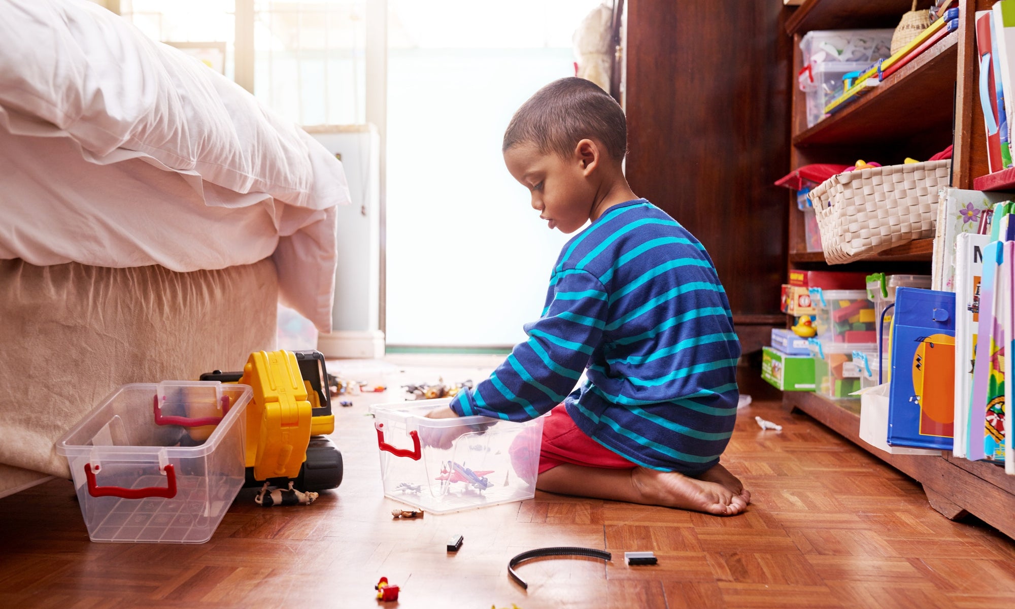 little boy sitting on bedroom floor and playing with toys