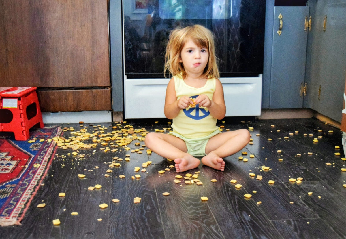 A child is eating snacks by sitting on floor