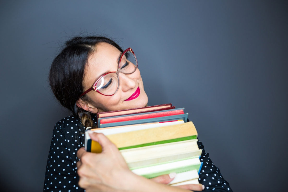 Woman resting her face on a pile of books.