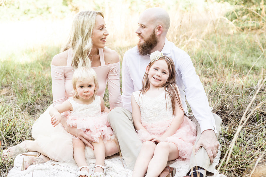 happy family sitting on flower field in park on a sunny day