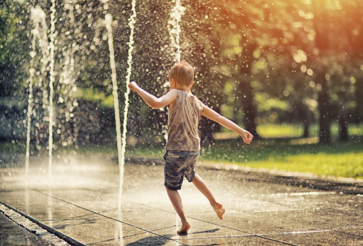 boy playing with water from a fountain 