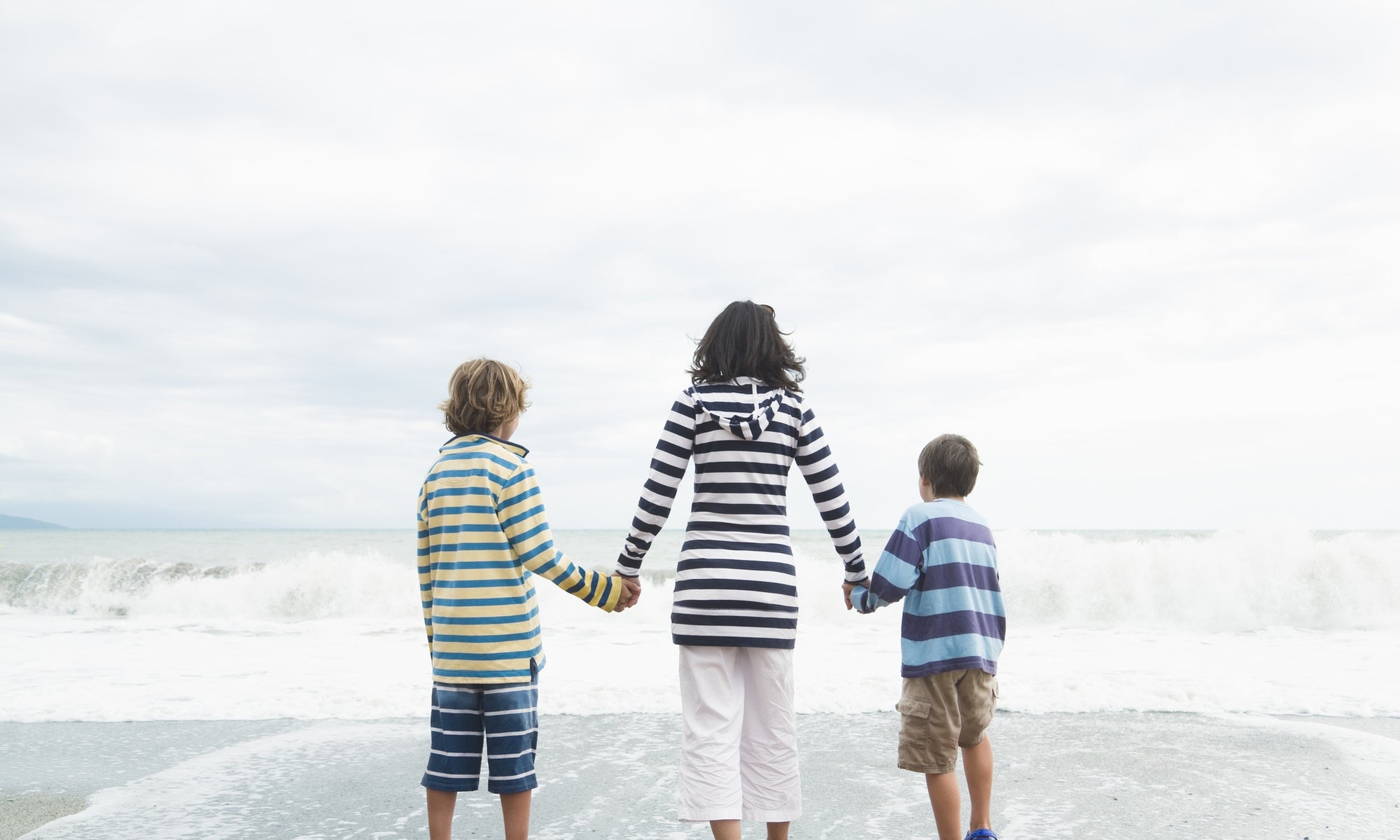 Mom And Her two sons Walk Hand In Hand At The Beach