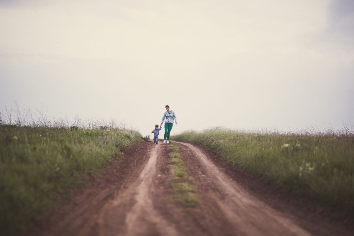 Baby child holding mother hand walking on road