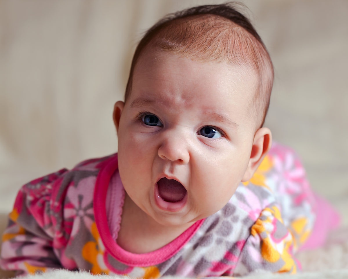 cute baby girl in pink dress lying on her stomach