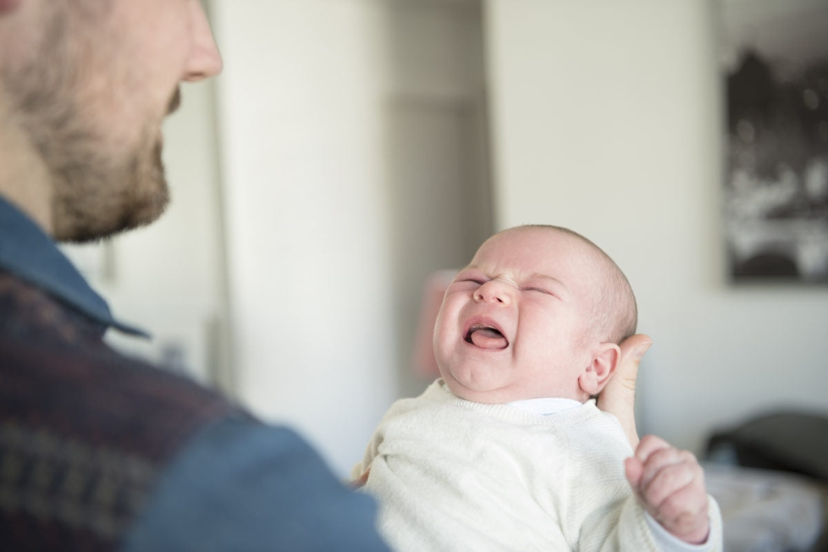 father holding crying new born baby