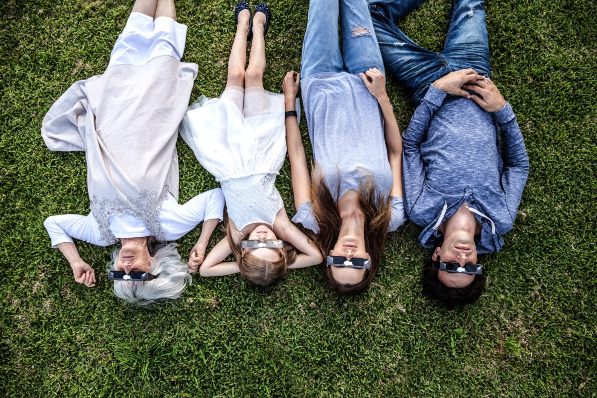 family members lying in the field wearing solar eclipse glasses