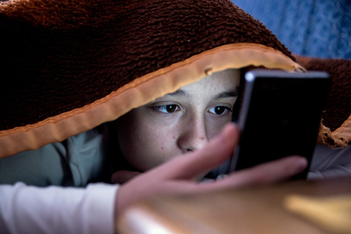 young boy checking smartphone throughout night