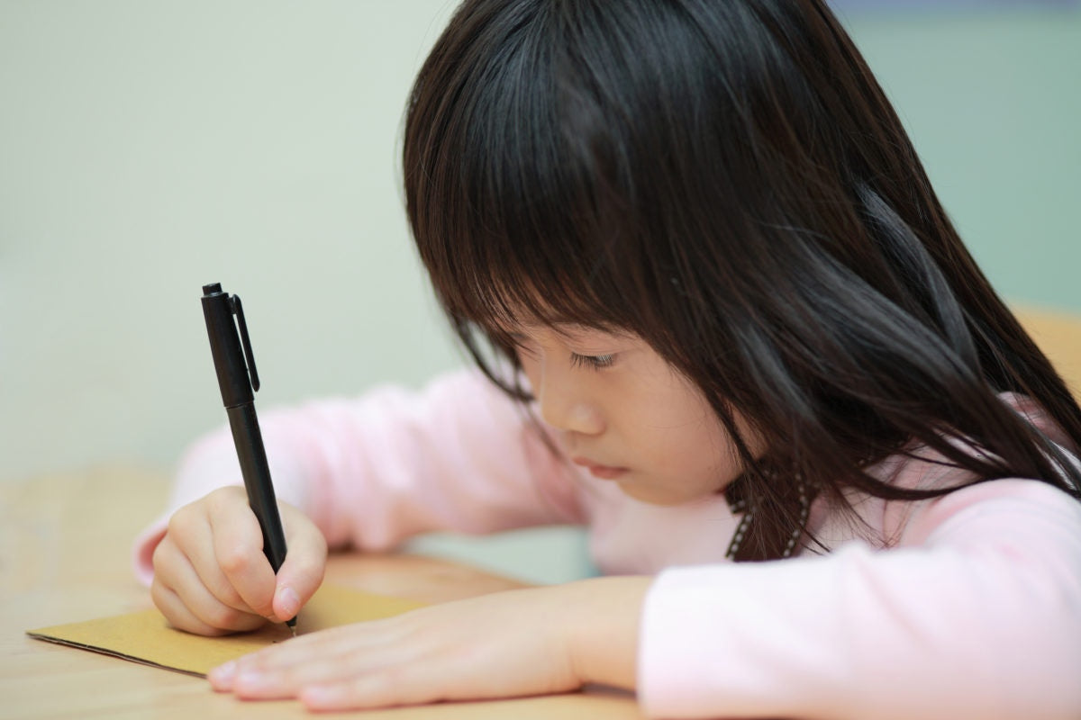 A child writing using pen