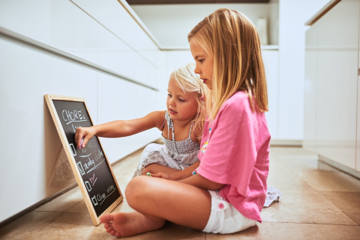 Two children writing on a black board