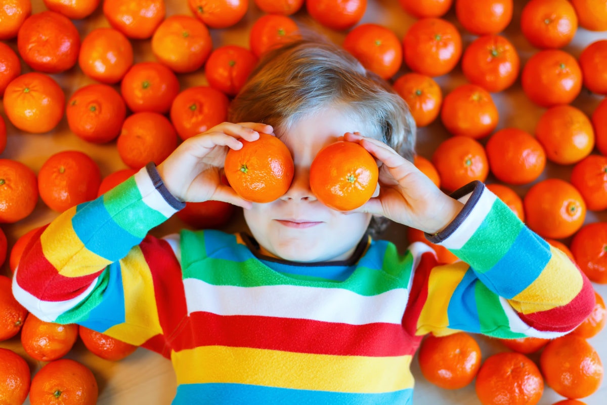 A child lying on fruits and holding two 