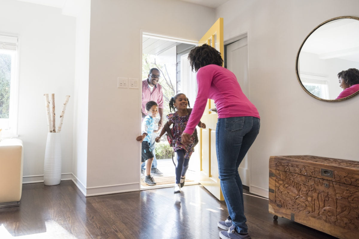 Children coming inside house to hug mother