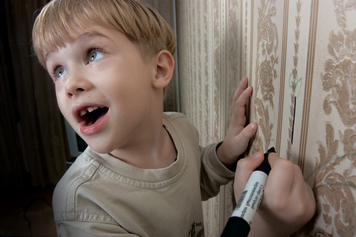 A kid drawing lines over the wall using a marker