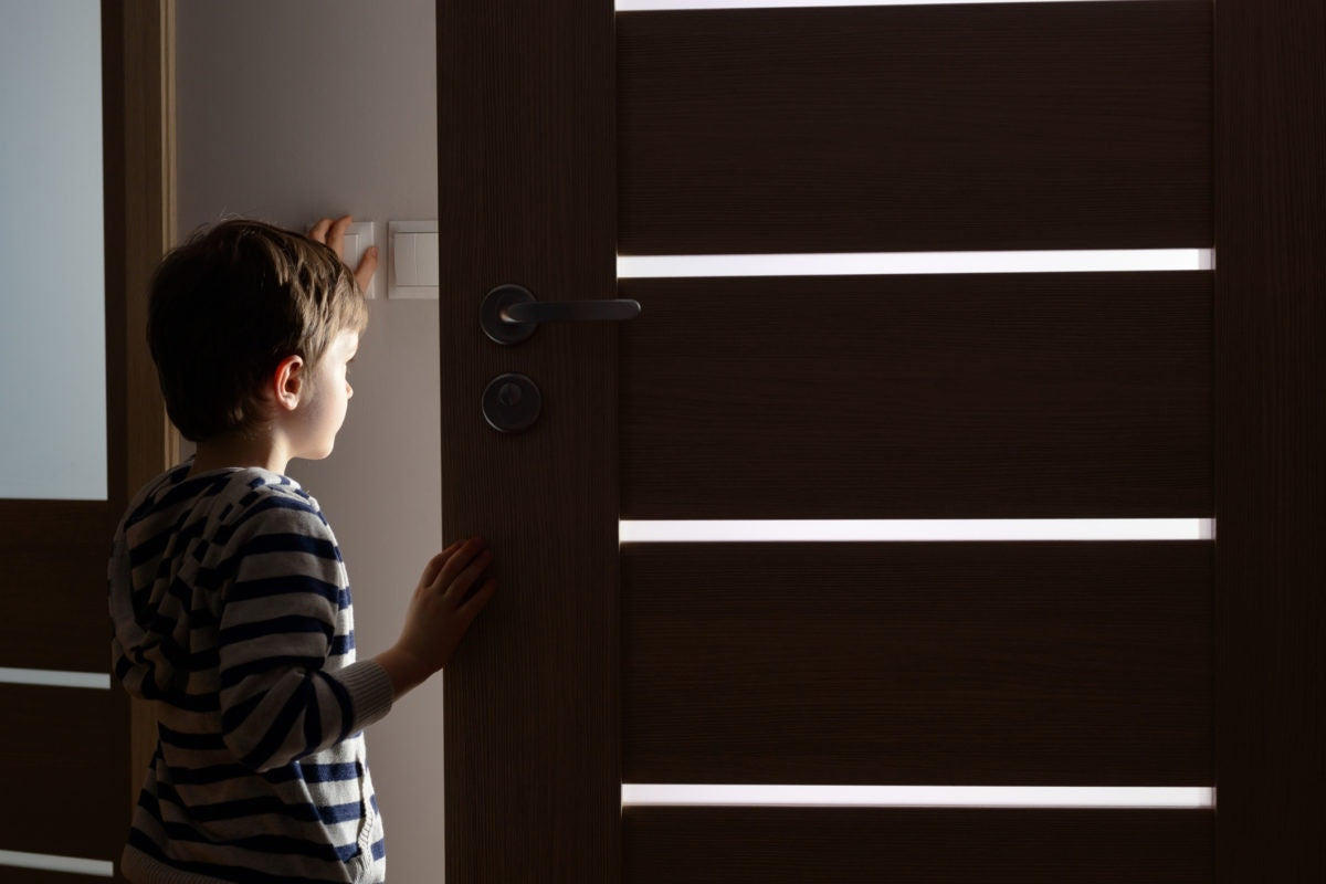 A baby watching out of a door