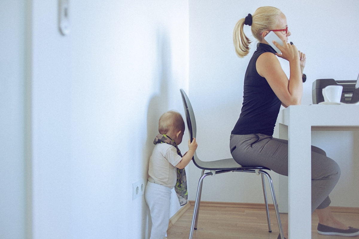 mother working and ignoring child who is behind her chair