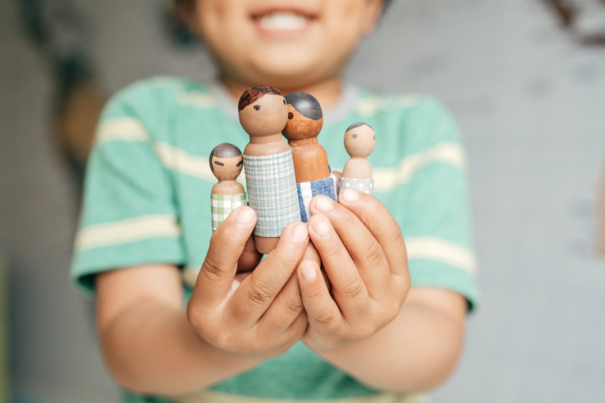 child holding small wooden toy family