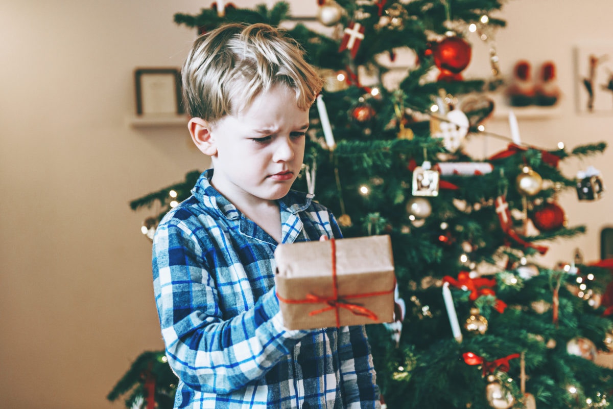 boy looking at a christmas looking not too happy