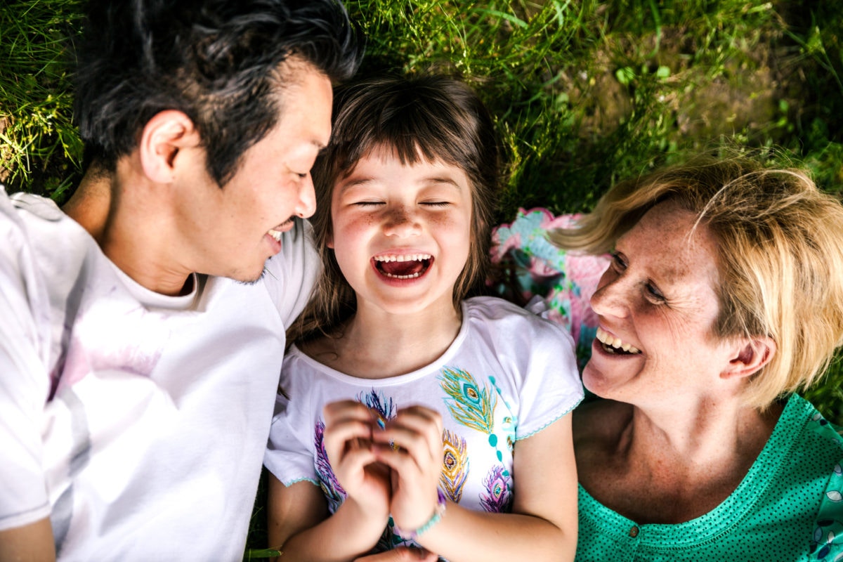 Happy family of three lying on grass