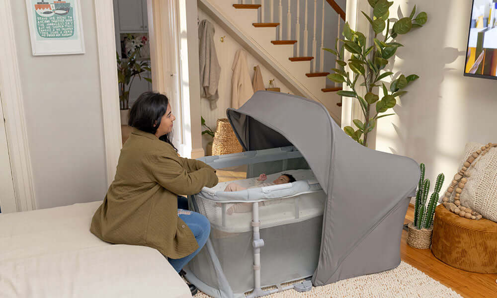 mother sitting next to crib to put baby to sleep