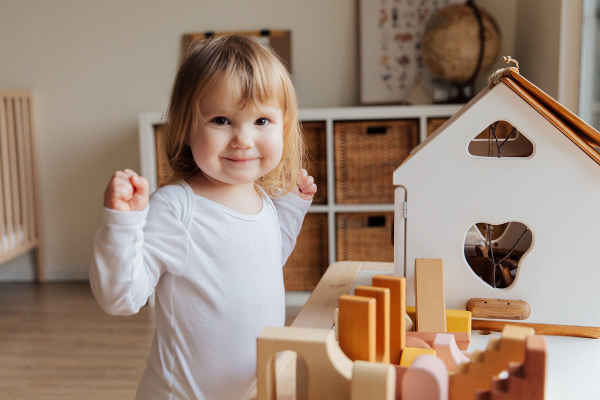 young girl next to a doll house