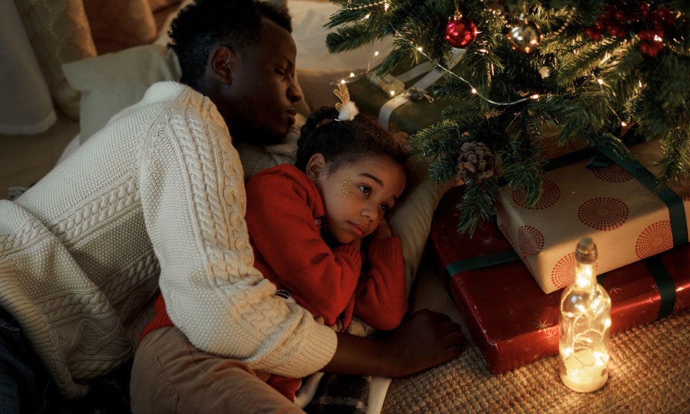 dad and daughter laying near christmas tree