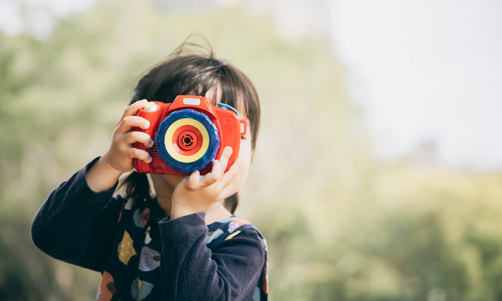 little girl playing with toy camera