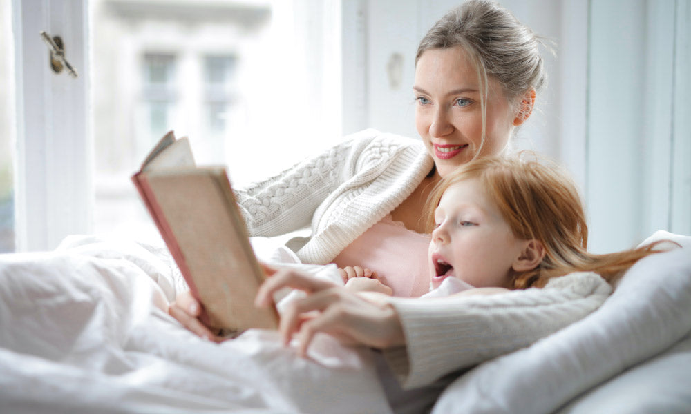Mutter und Tochter lesen ein Buch im Bett
