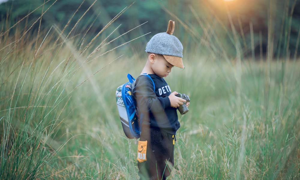 toddler with camera in the field