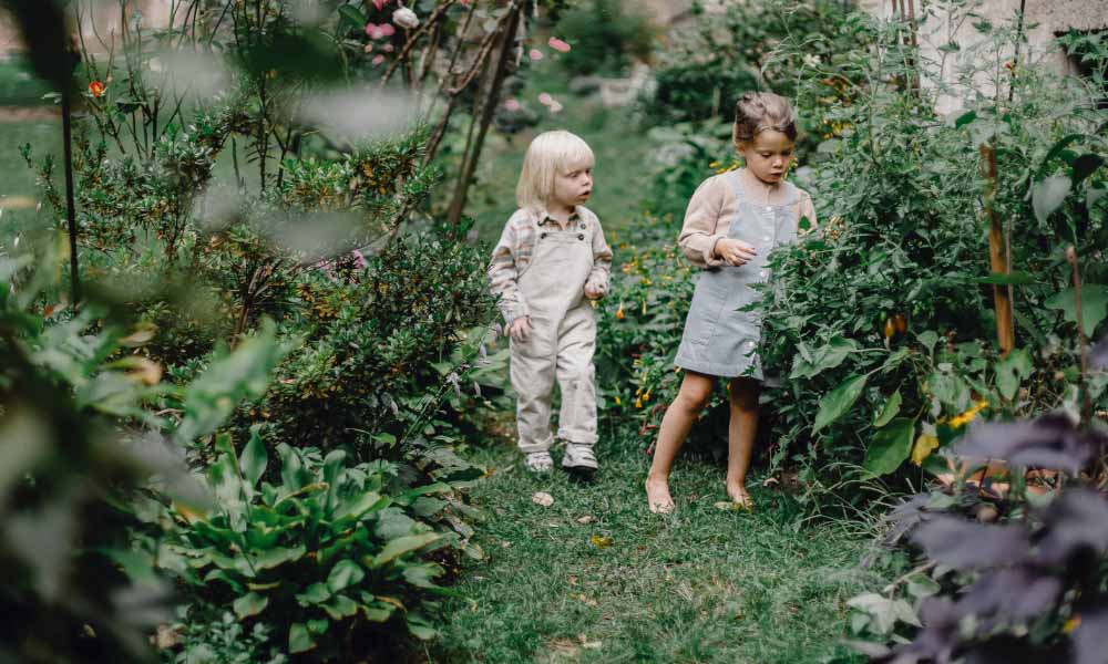 two kids walking through a garden